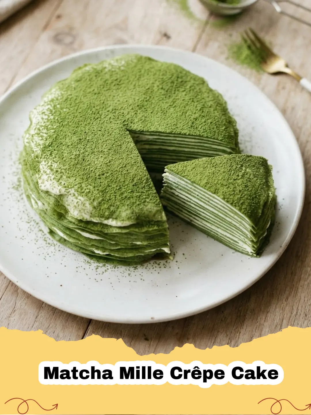 Matcha Mille Crêpe Cake - A beautifully layered matcha mille crêpe cake dusted with green matcha powder on a white cake stand, with a slice removed to show the delicate layers.