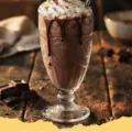 Chocolate Milkshake Recipe - Two tall glasses of classic homemade chocolate milkshake topped with whipped cream and chocolate shavings.