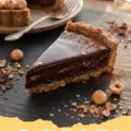 Chocolate Hazelnut Tart - A slice of decadent chocolate hazelnut tart on a white plate with a fork, showing the rich chocolate filling and nutty crust.